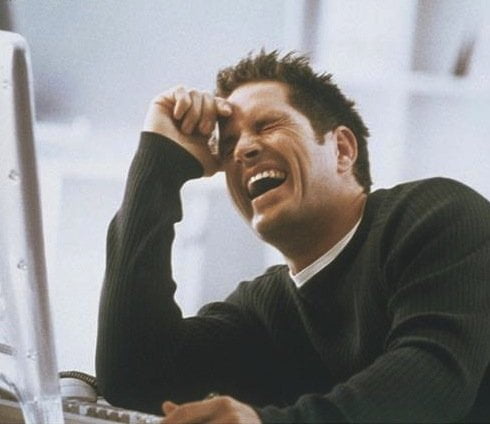 man_in_office_sitting_at_computer_hand_on_forehead_laughing_PBC13045