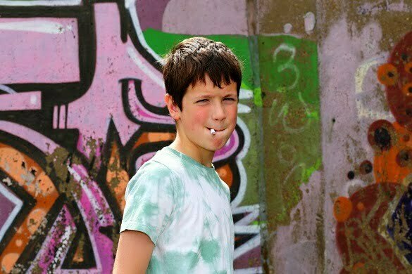 Boy smoking by graffiti wall